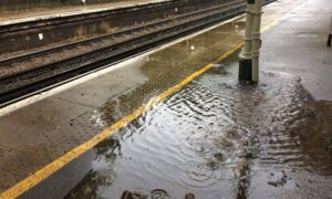 Flooded train station platform showing poor drainage design and safety risks after heavy rain.