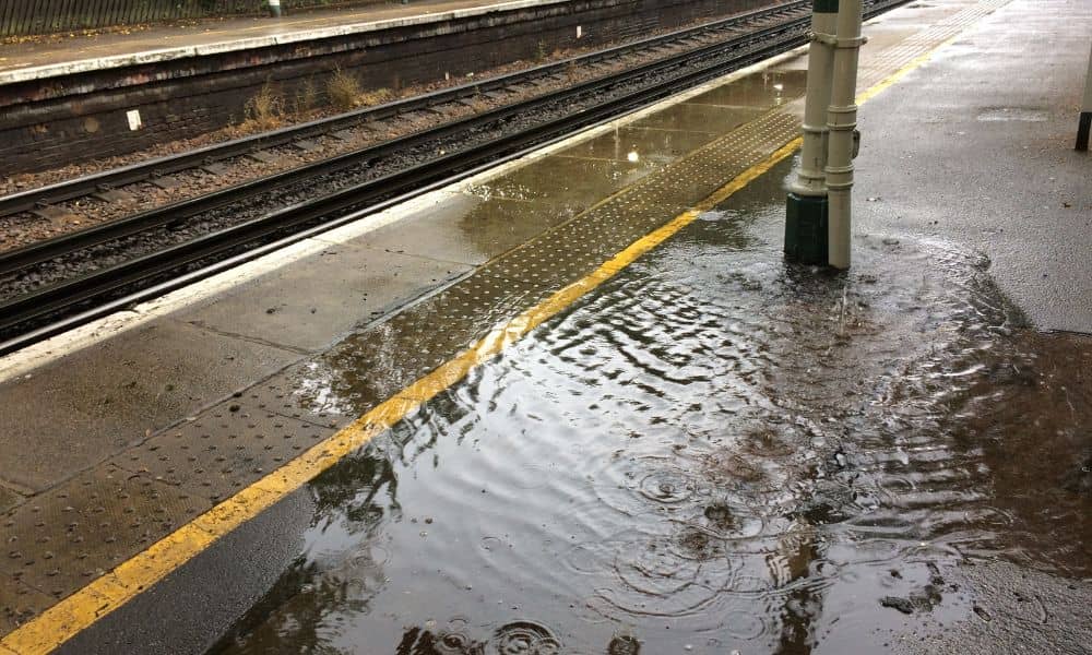 Flooded train station platform showing poor drainage design and safety risks after heavy rain.
