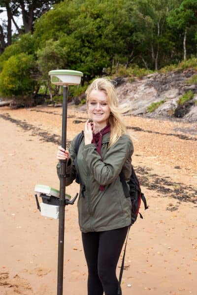 Land surveyor using GPS equipment near a coastal beach to update a flood elevation certificate after erosion
