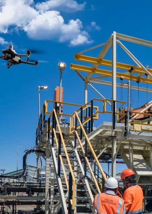Drone surveying industrial site - ALTA SURVEY North Carolina Licensed drone surveyor operating a drone over an industrial site with two surveyors observing the process.