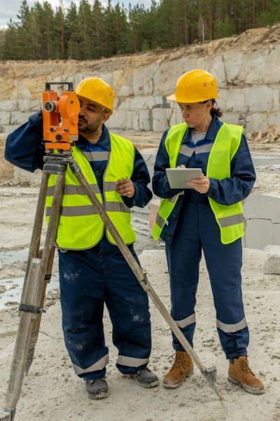  Surveyors performing a construction survey with a total station to verify site elevations and stormwater drainage compliance
