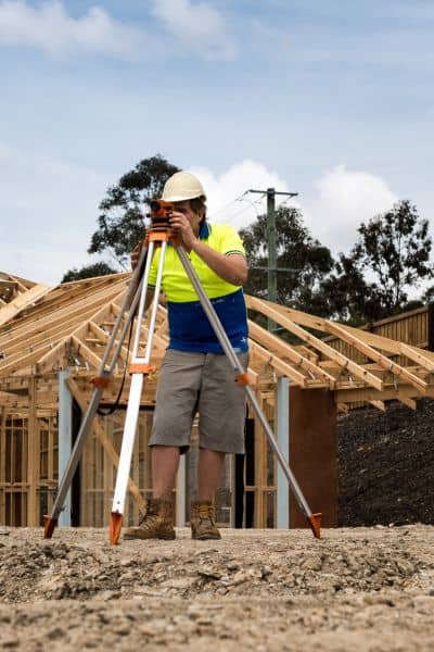 Surveyor measuring land elevation with tripod equipment to update elevation certificate and confirm flood safety standards