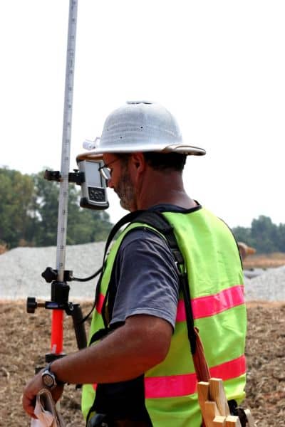 Professional land surveyor measuring elevation on site with survey equipment