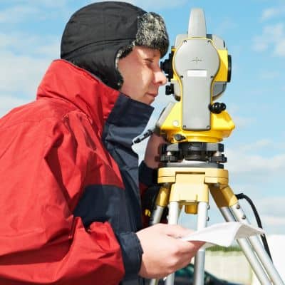 Licensed land surveyor using a total station to establish legal property boundaries
