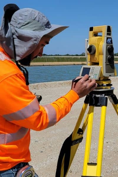 Surveyor using a total station to measure land in the field