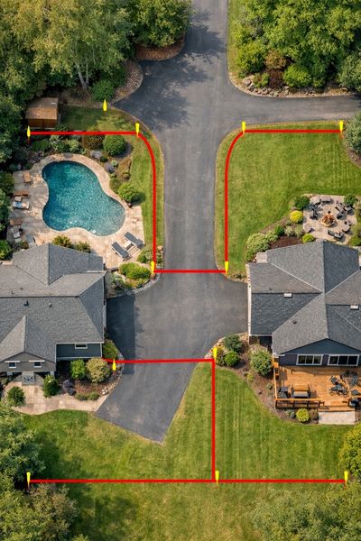 Boundary surveyor mapping property lines around a shared driveway between neighboring parcels
