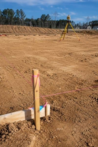 Survey stakes marking a building pad corner for elevation and layout checks in Wilmington NC
