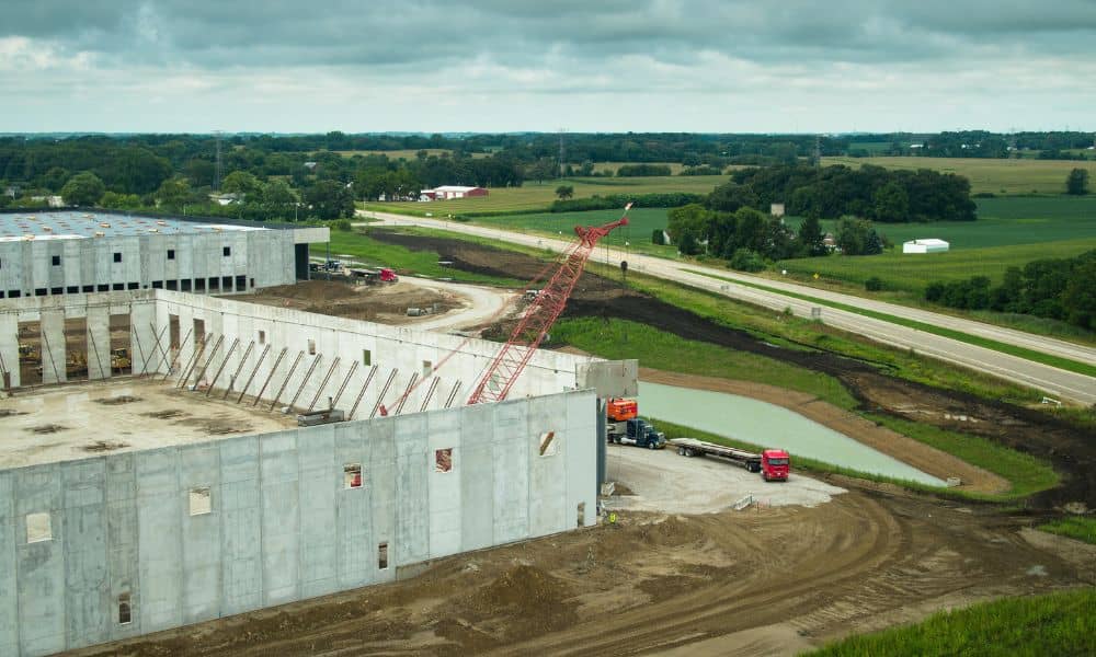 Tilt-up warehouse construction site with concrete wall panels and crane for construction survey
