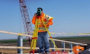 Surveyor operating a total station at a construction site, with equipment used for elevation surveys