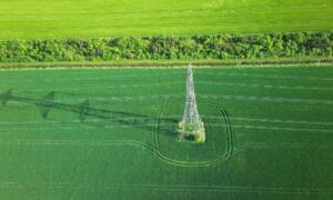 Aerial view of a transmission tower and power lines crossing farmland, illustrating how LiDAR mapping can support transmission corridor planning
