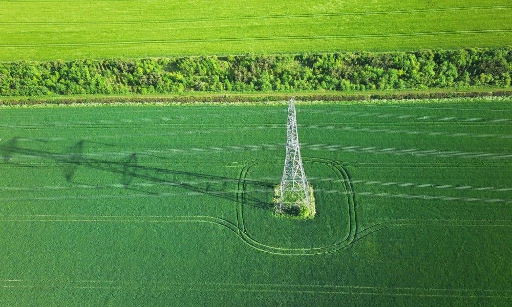 Aerial view of a transmission tower and power lines crossing farmland, illustrating how LiDAR mapping can support transmission corridor planning
